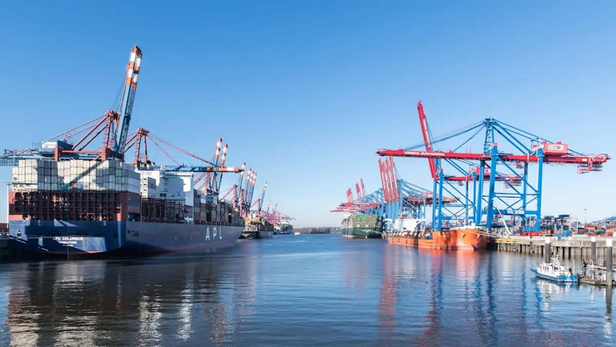 Container ship at a port terminal with rock bags visible at the berth toe